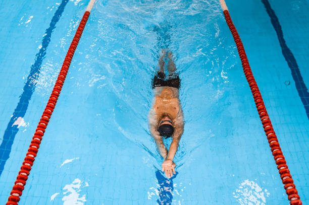 istock Swimmer floating in the swimming pool, top view. Relaxing bode on blue water pool 1285321190