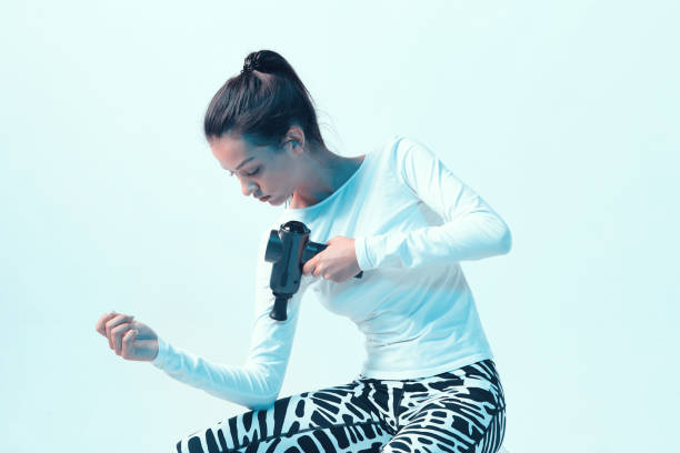 istock Percussion massager, athletic young brunette female massaging hand in neon studio light 1285322157