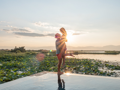 Couple enjoying tropical vacations from the edge of an infinity pool. People travel luxury holidays