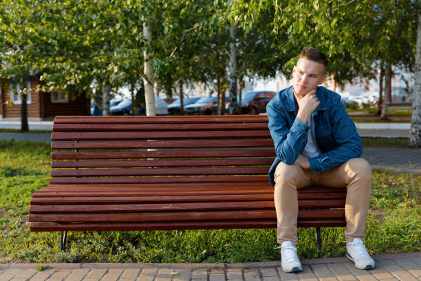 istock Young man sits on a park bench with a pensive look. Copyspace. 1285322889
