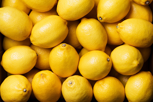 Fresh lemon background. Top view. Citrus fruits. Vitamins for health. Box of yellow lemons. Liposomal vitamin C.
