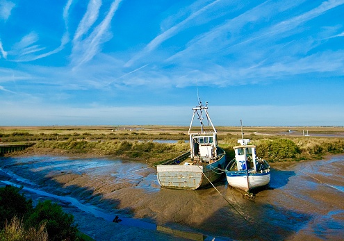 Boat on water channel at low tide on mudflats in north Norfolk.