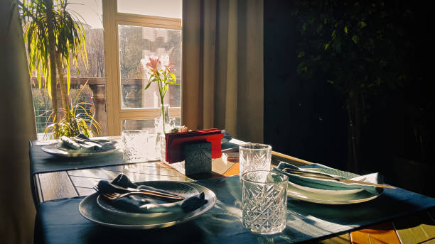 istock Table setting for romantic breakfast in the morning sun through a window. Shadows and sunbeams in dark room. 1285324313