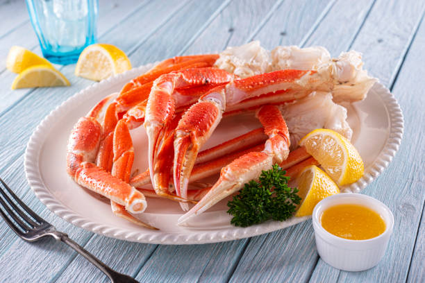 Snow Crab Clusters A plate of delicious snow crab leg clusters with lemon, parsley and melted butter. snow crab photos stock pictures, royalty-free photos & images