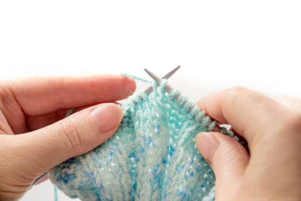 istock Female hands with holding knitting needles close up isolated on white background. 1285326579