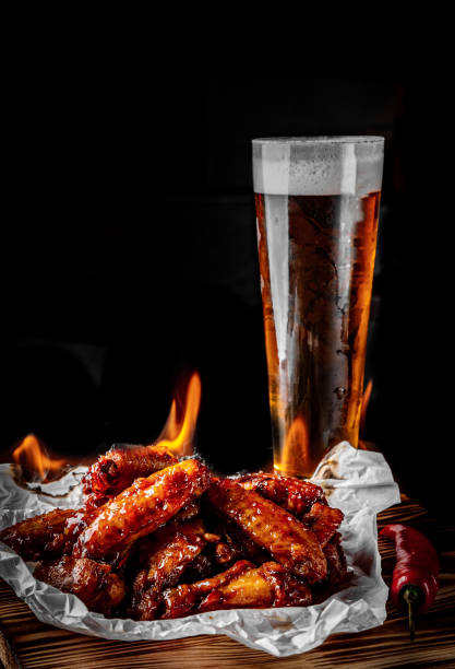 szklanka świeżego piwa i smażone skrzydełka kurczaka na drewnianym stole na czarnym tle - beer wing spicy chicken wings chicken wing zdjęcia i obrazy z banku zdjęć