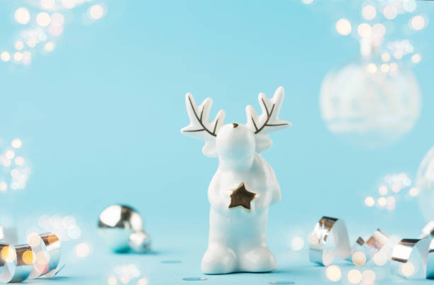 istock Christmas card with small glass white deer, silver decorations, mirror disco balls on light blue background. 1285327781