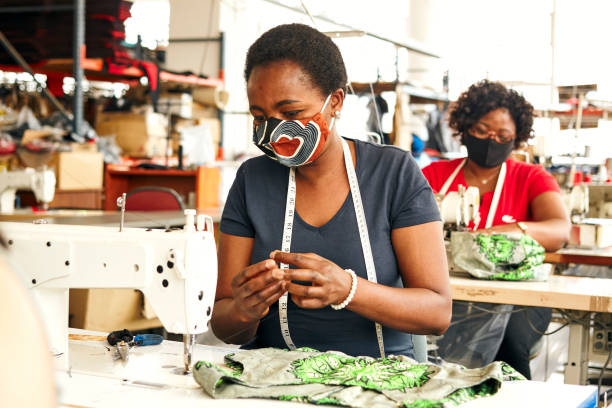 working the line in pandemic - factory garment sewing textile imagens e fotografias de stock