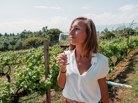 Woman tasting red wine in vineyard smelling the aroma