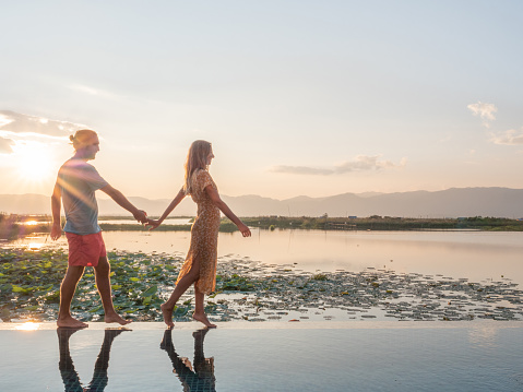 Couple enjoying tropical vacations from the edge of an infinity pool. People travel luxury holidays