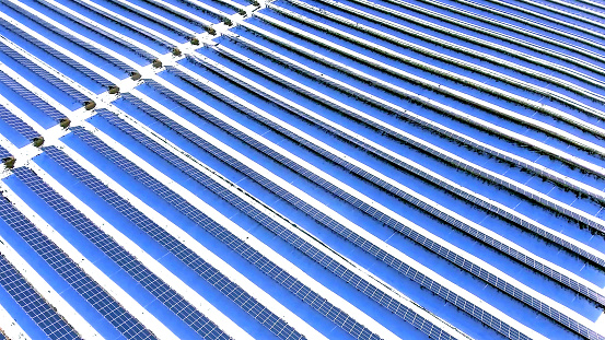 blue photovoltaic solar energy panels and the snow during winter.
