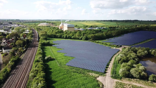 Solar Panels farm and the train rail way Solar Panels farm and green field next to the train rail way solar panel manufacturing stock pictures, royalty-free photos & images
