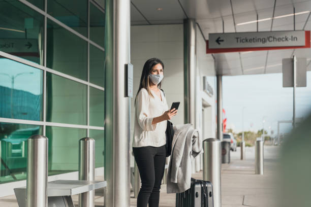 istock Outside terminal, young woman, wearing  protective mask, waits for ride 1285331876