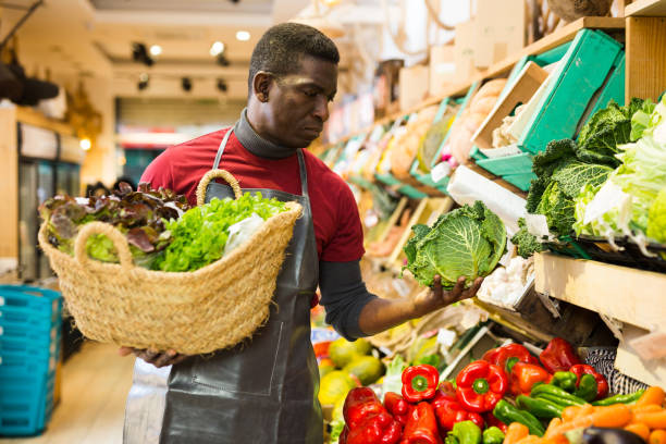 istock Seller arranging leafy vegetables on counter 1285335825