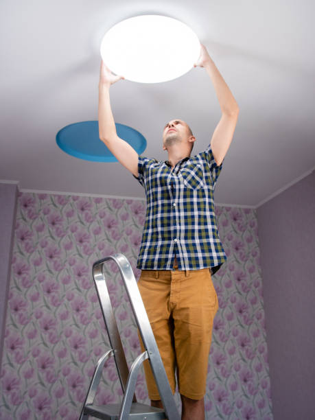 istock A man with a stepladder sets the ceiling lamp in the room. 1285336781