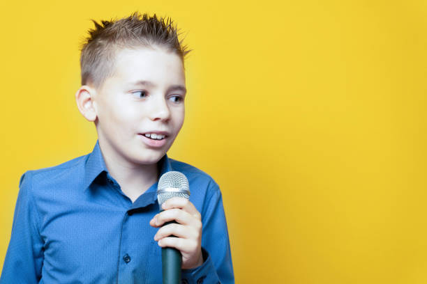 istock Boy with a microphone on a yellow background, close-up 1285337091