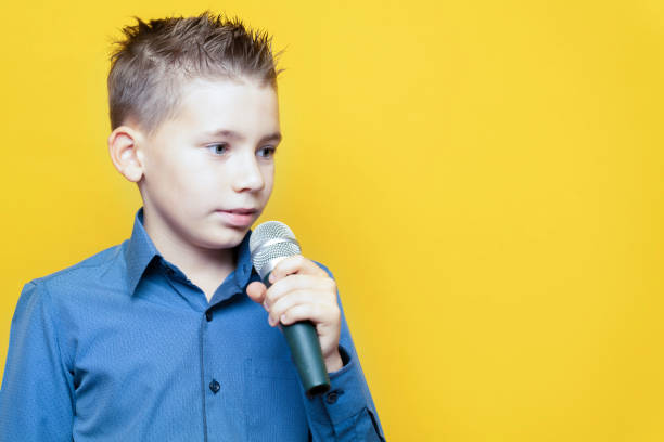 istock Boy with a microphone on a yellow background, close-up. Copy space 1285337096