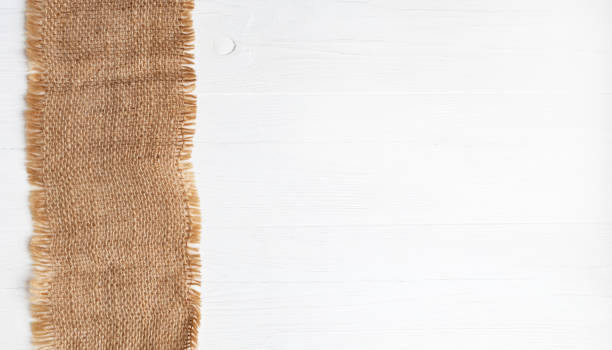 Rough linen napkin on a white wooden background with space for text. Layout.