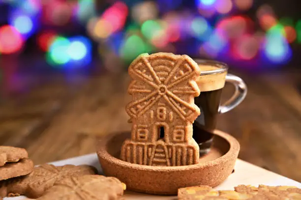 Speculaas koekjes and espresso for st. Nicolas day the background of festive garlands. Dutch holiday Sinterklaas traditional sweets gingerbread cookies. 5th December holiday in the Netherlands.