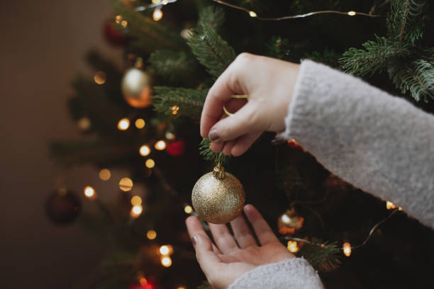 istock Decorating christmas tree with modern golden bauble in festive decorated room with lights 1285351323