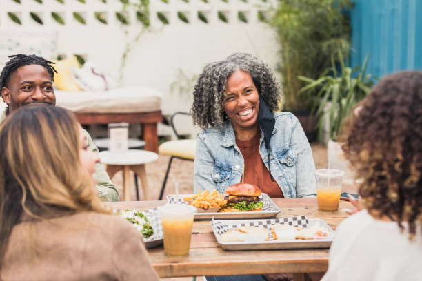 다양한 친구들이 파티오 레스토랑에서 식사를 하면서 웃는다. - dining burger outdoors restaurant 뉴스 사진 이미지
