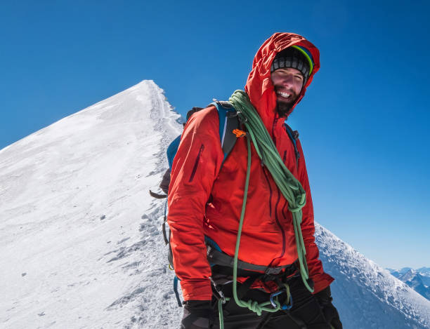 istock Rope team happy smiling man in climbing harness dressed red mountaineering clothes Last steps before Mont Blanc (Monte Bianco) summit 4808 m on the snowy slopes with a blue sky background. 1285357177