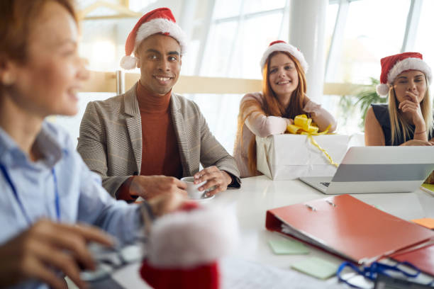 istock workers looking at their boss with smile wearing santa hats 1285359834