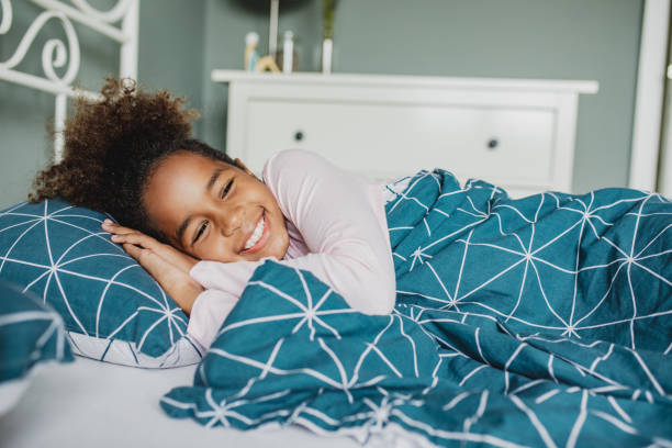 istock A little girl is waking up in bed with smile 1285362632