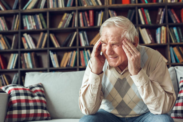 istock Senior man alone sitting at library having terrible headache 1285369486