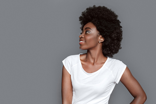 Young african woman standing isolated on gray looking aside smiling cheerful close-up