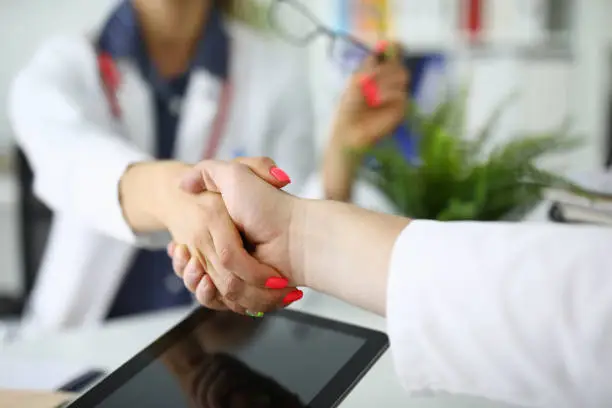 Photo of Female doctor shakes hands with her colleague.