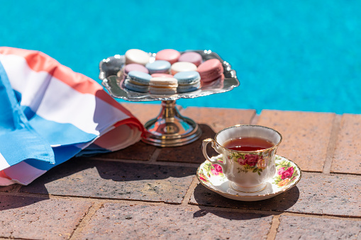 Luxury Concept of Tea and French Macarons on a Silver Tray by a Swimming Pool