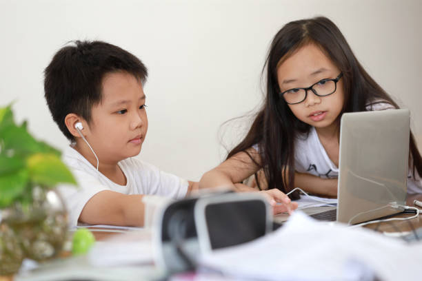 istock Little Asian boy and girl using computer laptop learning at home 1285387383