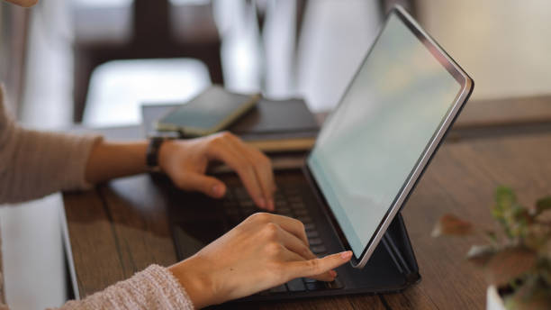 istock Female hands typing on tablet keyboard on wooden table, include clipping path 1285387611