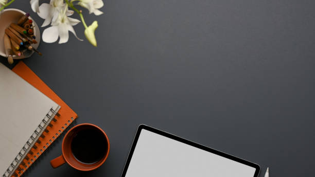 istock Workspace with tablet, notebooks, coffee mug, copy space and flower decorated on the table 1285387648