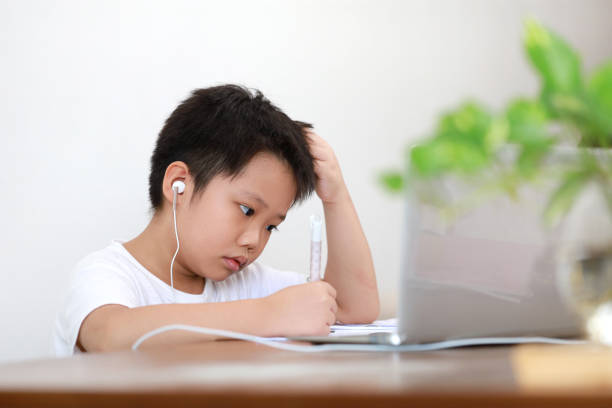 istock Portrait of a little Asian boy student using computer laptop learning at home 1285390386