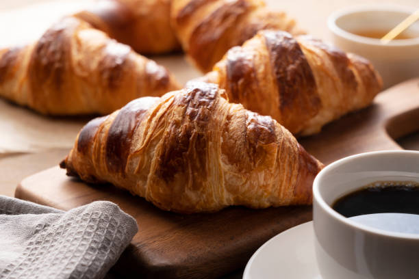 istock Croissants and coffee on a wooden cutting board 1285396716