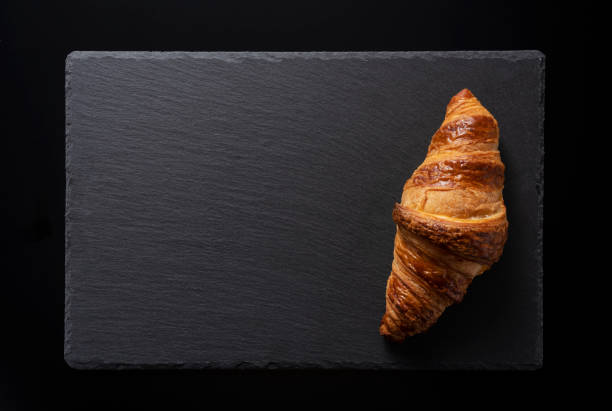 istock Croissant on a black stone plate with a black background 1285397542