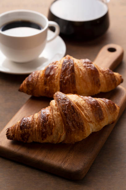 istock Croissants and coffee on a wooden cutting board 1285397566