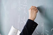 A Japanese woman teacher writes on the blackboard in her classroom