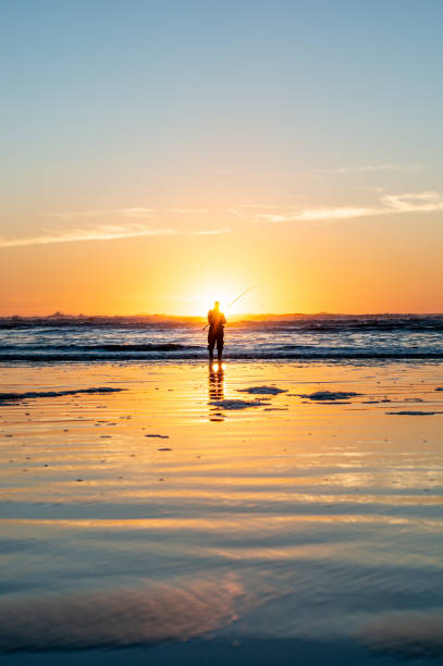 istock Fishing in the Sunset by the Pacific Ocean Shore 1285407905