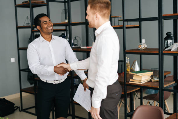 istock Diverse business partners shaking hands in agreement standing in office hall. 1285411100