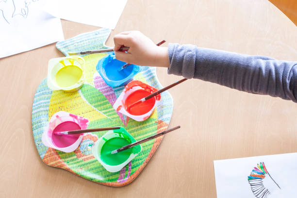 istock Child hand soaking artist brush on Washable Tempera paint 1285413029