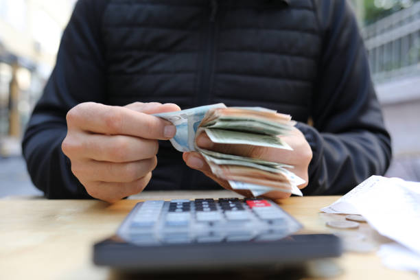 istock man doing financial transactions with calculator holding money 1285416582