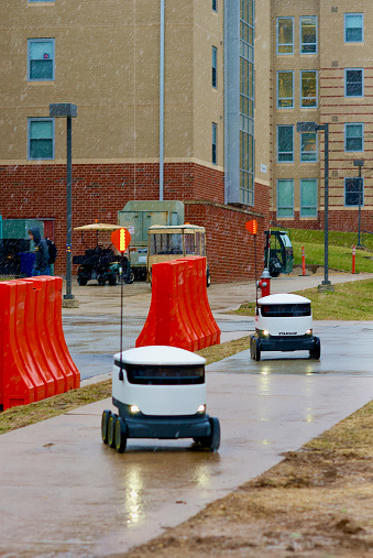 Fairfax, Virginia / USA - January 29, 2019: Autonomous food delivery robots made by Starship Technologies cross the George Mason University main campus in falling snow to their next destination.