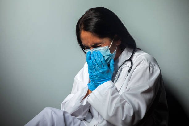 istock A desperate nurse wearing a protective mask coughs while working in a clinic during the COVID-19 SARS-CoV-2 coronavirus epidemic. 1285418132