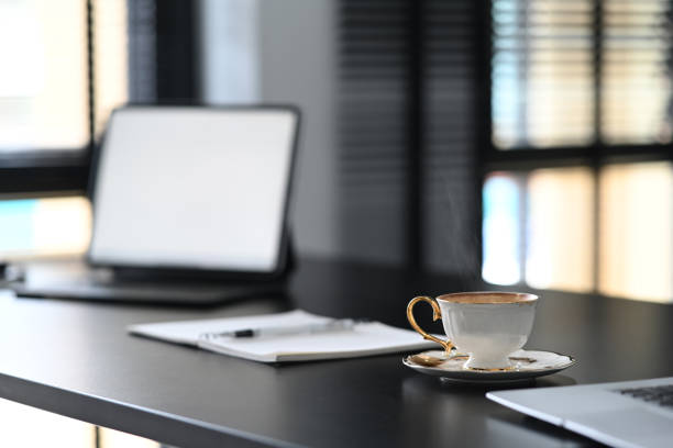 istock A white coffee cup is putting on contemporary workspace with empty screen computer laptop on blace wooden table. 1285419325