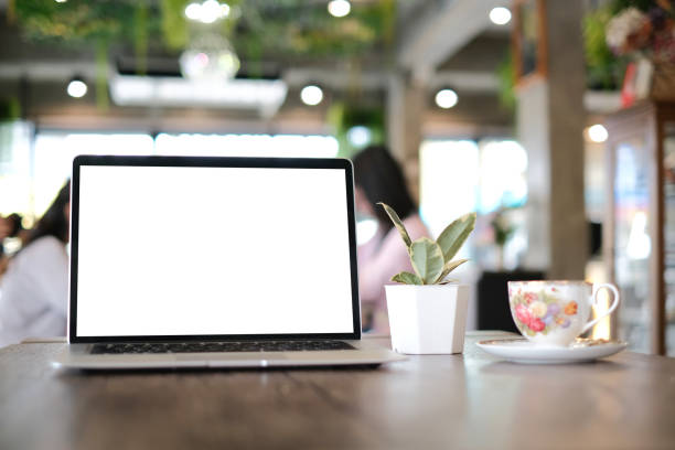 istock Front view of sinple workspace with isolated white display laptop, plant and coffee cup on blured office room background. 1285419856