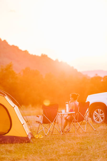 istock woman looking at sunset above mountains river. camping concept 1285420873