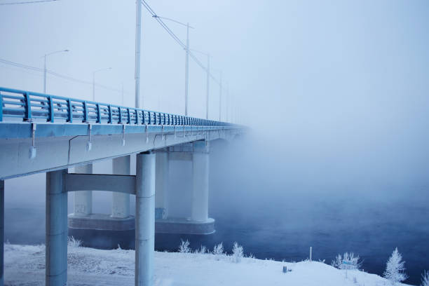 Winter frosty morning in Siberia. View of the bridge and river in the fog.